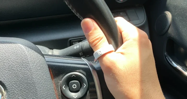 Oura Ring 4サイジングキットのサイズ10(USモデル)を右手の親指に装着し自動車のハンドルを持っている様子
