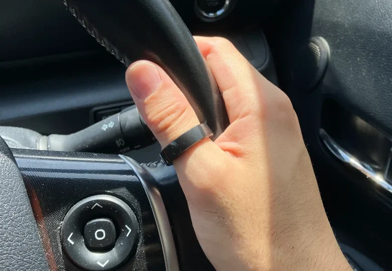 RinnConnサイジングキットのサイズ10(USモデル)を右手の親指に装着し自動車のハンドルを持っている様子