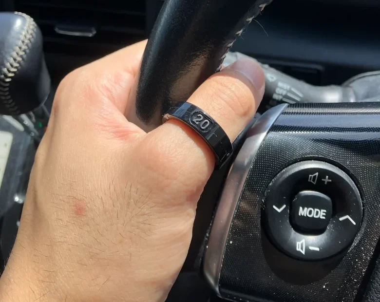 SOXAI RING 2サイジングキットのサイズ20を左手の親指に装着し自動車のハンドルを持っている様子