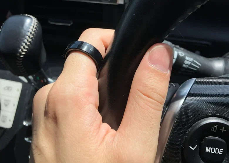 SOXAI RING 2サイジングキットのサイズ20を左手の人差し指に装着し自動車のハンドルを持っている様子